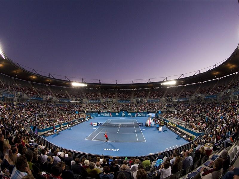 A full tennis court pictured at night with a purple background